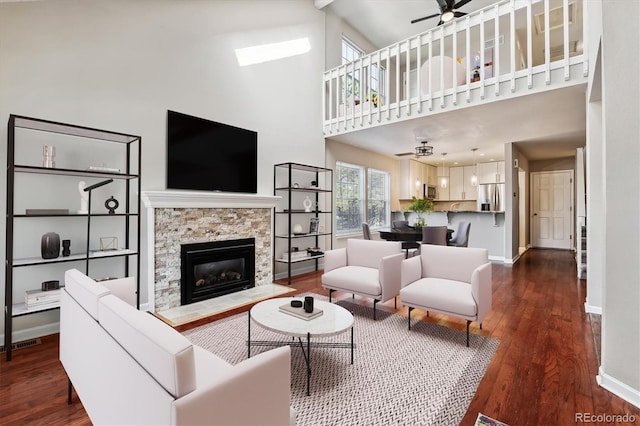 living room with visible vents, baseboards, ceiling fan, a fireplace, and dark wood-style flooring