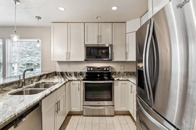 kitchen featuring a sink, light stone counters, appliances with stainless steel finishes, and white cabinetry