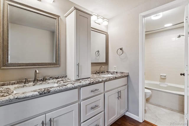 full bathroom featuring a sink, toilet, tub / shower combination, and double vanity