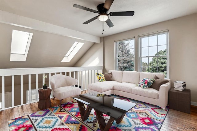 living area featuring lofted ceiling with skylight, hardwood / wood-style flooring, and a ceiling fan