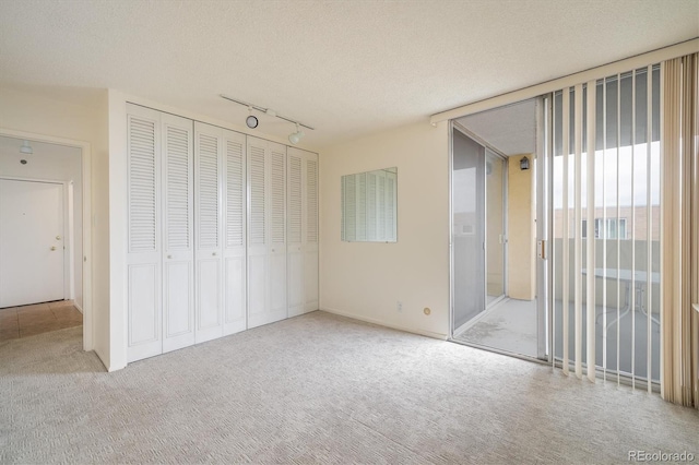 850 20th St Unit 203, Boulder, CO 80302 - unfurnished bedroom with carpet floors, rail lighting, a closet, a textured ceiling, and access to outside