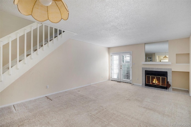 unfurnished living room with carpet, french doors, a textured ceiling, and a fireplace