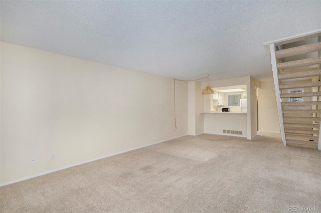 unfurnished living room featuring carpet flooring and a textured ceiling