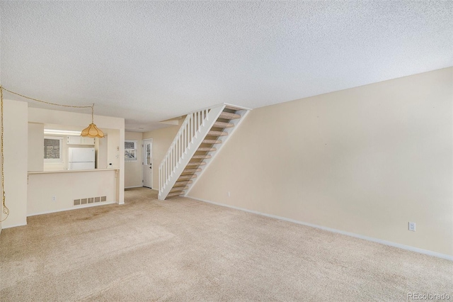 unfurnished living room featuring carpet floors and a textured ceiling