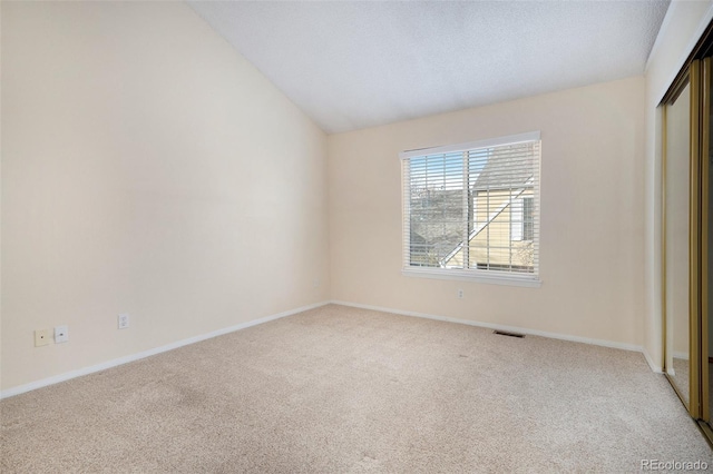 unfurnished bedroom featuring light carpet, a textured ceiling, a closet, and lofted ceiling