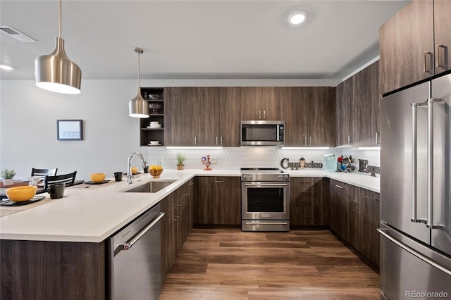 kitchen with high end appliances, sink, pendant lighting, and dark brown cabinets