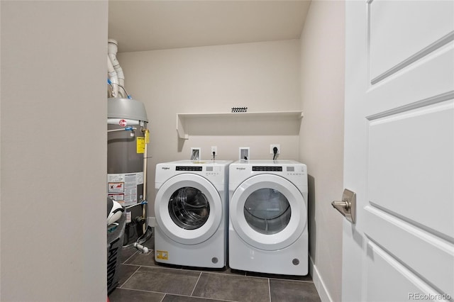 laundry area featuring dark tile patterned floors, gas water heater, and separate washer and dryer