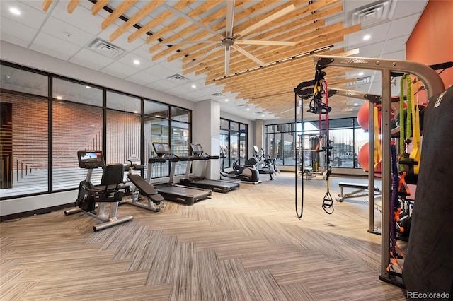 exercise room featuring a paneled ceiling and carpet flooring