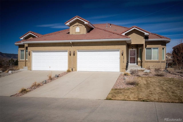 view of front of house with stucco siding, concrete driveway, an attached garage, and a tiled roof