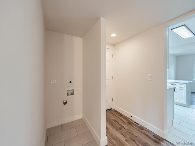 clothes washing area with light hardwood / wood-style floors, hookup for a washing machine, and electric dryer hookup