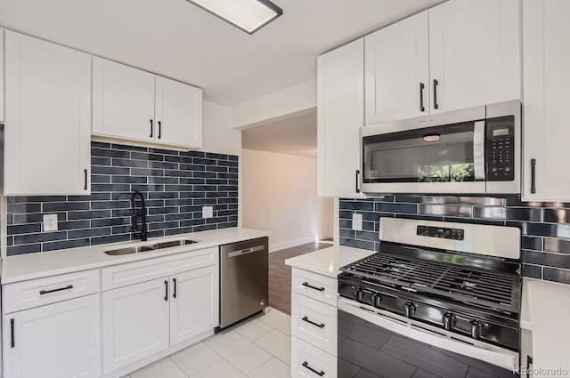 kitchen featuring white cabinets, stainless steel appliances, decorative backsplash, and sink