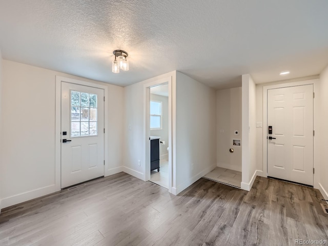 entryway with a textured ceiling and light hardwood / wood-style flooring