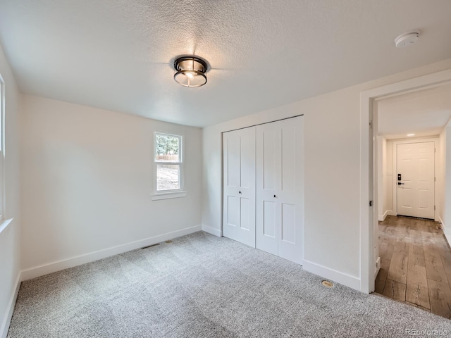 unfurnished bedroom featuring a textured ceiling, hardwood / wood-style floors, and a closet