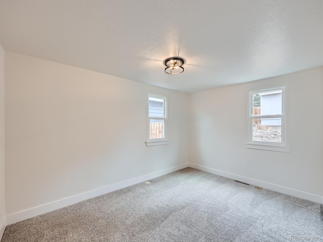 carpeted spare room with a textured ceiling