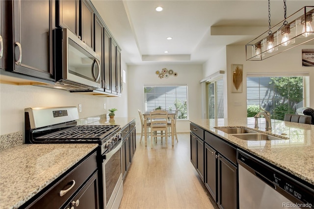 6717 Golden Briar Ln, Colorado Springs, CO 80927 - kitchen featuring appliances with stainless steel finishes, a sink, light wood-style flooring, light stone counters, and a raised ceiling