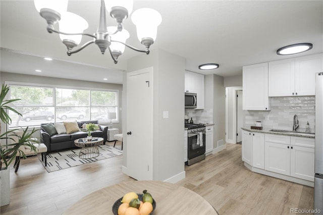 740 Moline St, Aurora, CO 80010 - kitchen with appliances with stainless steel finishes, a chandelier, white cabinets, light wood finished floors, and decorative backsplash
