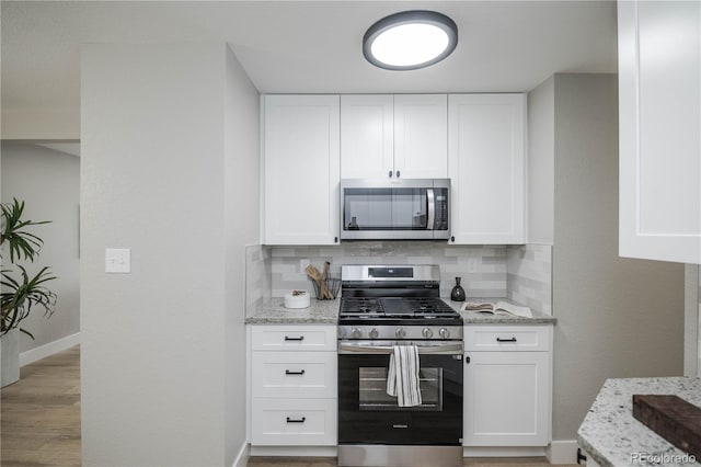 740 Moline St, Aurora, CO 80010 - kitchen featuring appliances with stainless steel finishes, light stone counters, tasteful backsplash, white cabinets, and baseboards