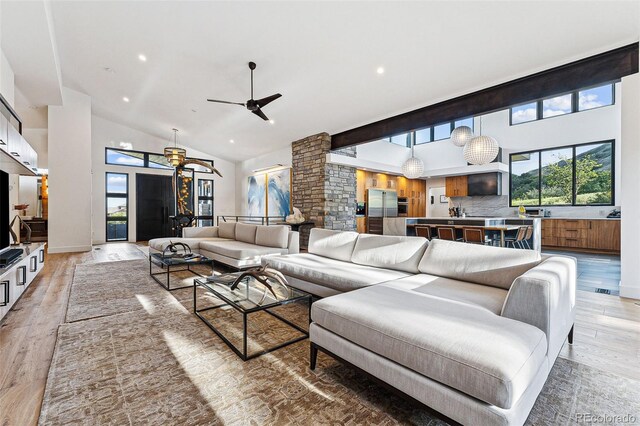 living room featuring high vaulted ceiling, light hardwood / wood-style floors, and ceiling fan