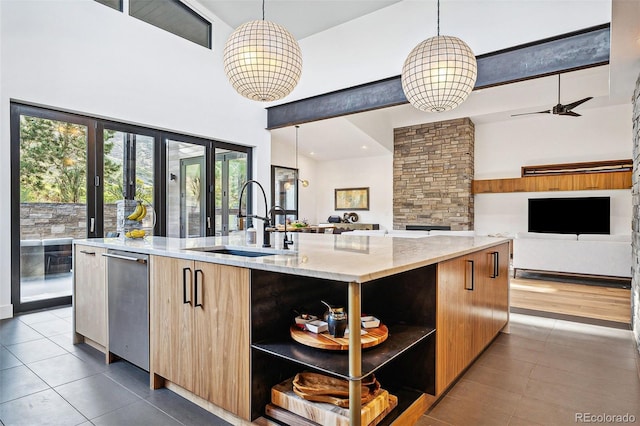 kitchen featuring a towering ceiling, a center island with sink, hanging light fixtures, and sink