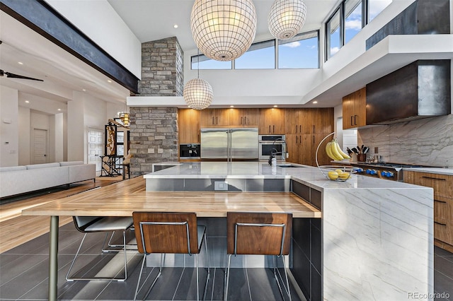 kitchen featuring dark tile patterned flooring, exhaust hood, stainless steel appliances, and tasteful backsplash