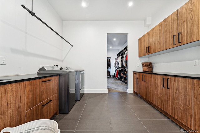 washroom featuring washer and clothes dryer, dark tile patterned flooring, and cabinets