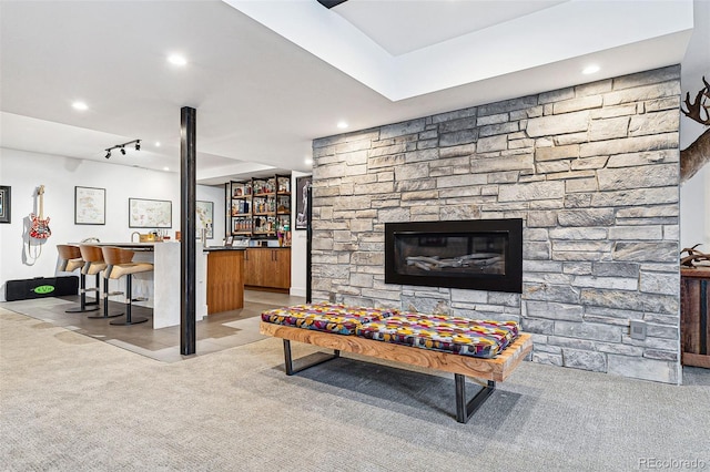 carpeted living room with a stone fireplace