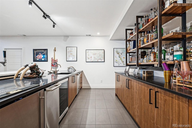 kitchen featuring light tile patterned floors, beverage cooler, sink, and rail lighting