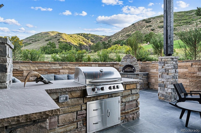 view of patio / terrace featuring a mountain view, an outdoor kitchen, and grilling area