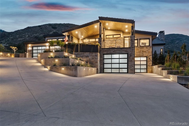 contemporary home with a balcony, a mountain view, and a garage