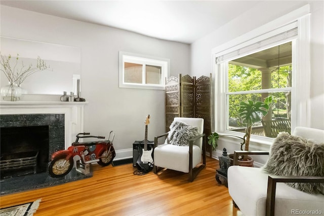 sitting room featuring wood finished floors, a high end fireplace, and baseboards