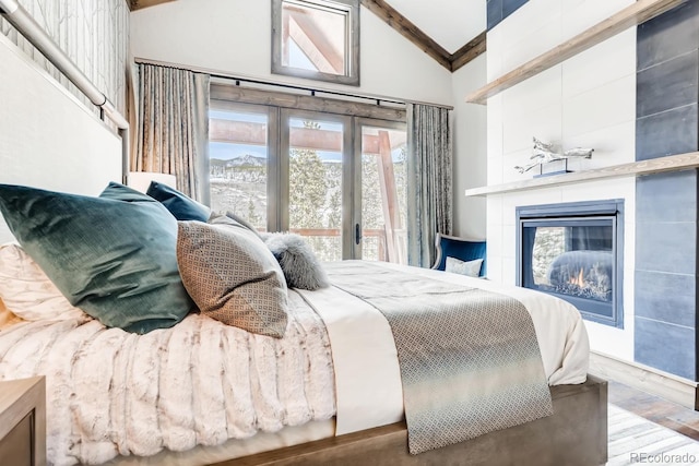 bedroom featuring vaulted ceiling with beams, access to outside, wood finished floors, and a tile fireplace