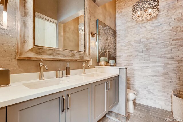 bathroom with double vanity, a sink, and toilet