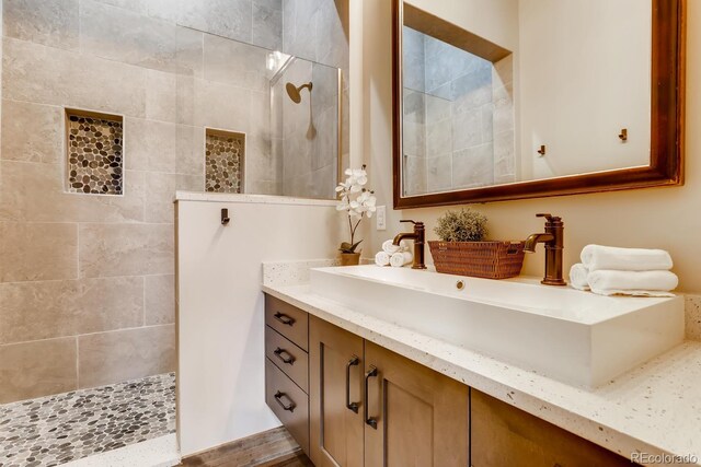 bathroom featuring a walk in shower and vanity