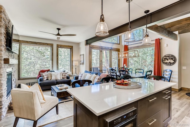 kitchen with light wood-style floors, open floor plan, light countertops, hanging light fixtures, and a center island