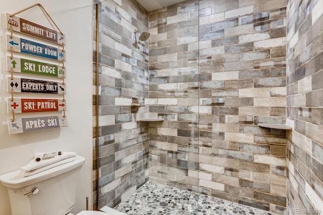 bathroom featuring a tile shower and toilet