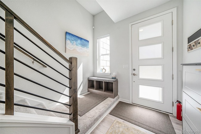 entrance foyer with baseboards, wood finished floors, and stairway