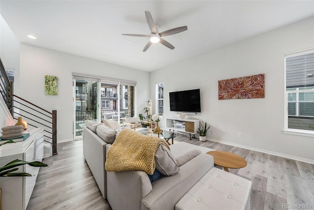 living area featuring a ceiling fan, light wood-type flooring, stairs, baseboards, and recessed lighting