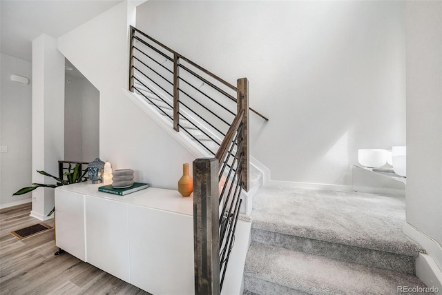 stairway with visible vents, baseboards, and wood finished floors