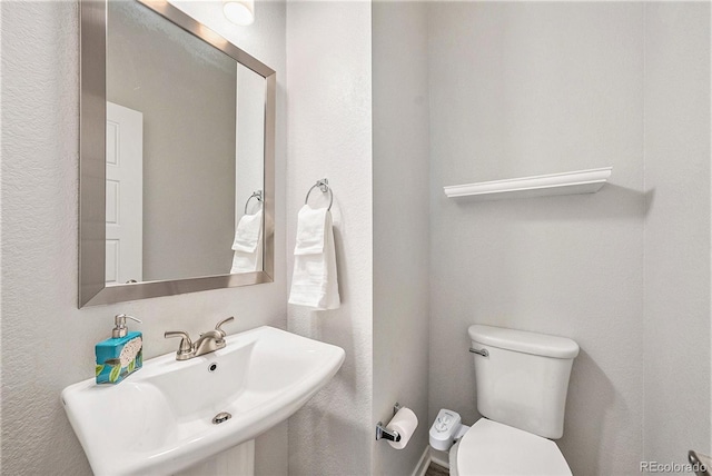 half bathroom featuring toilet and a sink