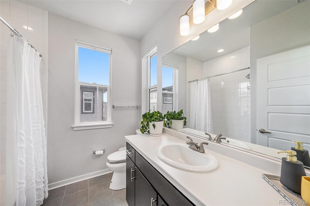 bathroom with a tile shower, tile patterned flooring, vanity, toilet, and baseboards