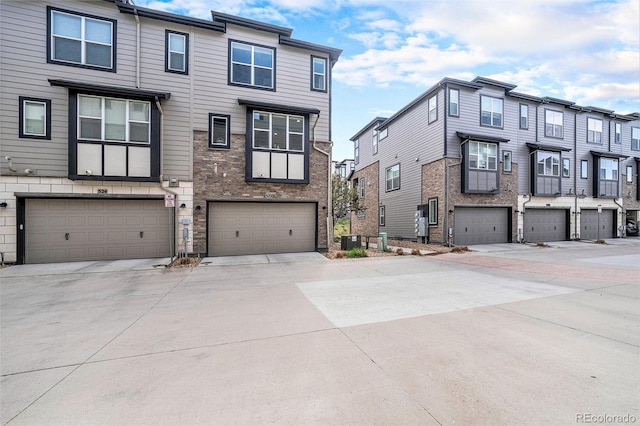townhome / multi-family property with an attached garage, driveway, a residential view, and central AC