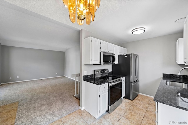 kitchen featuring white cabinetry, light carpet, sink, appliances with stainless steel finishes, and a textured ceiling