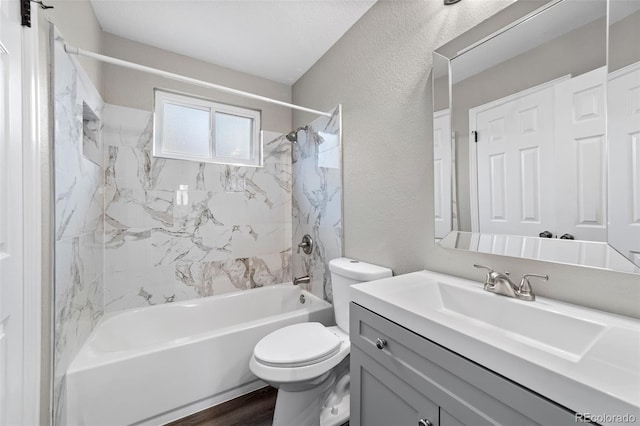 full bathroom featuring wood-type flooring, vanity, a textured ceiling, toilet, and tiled shower / bath