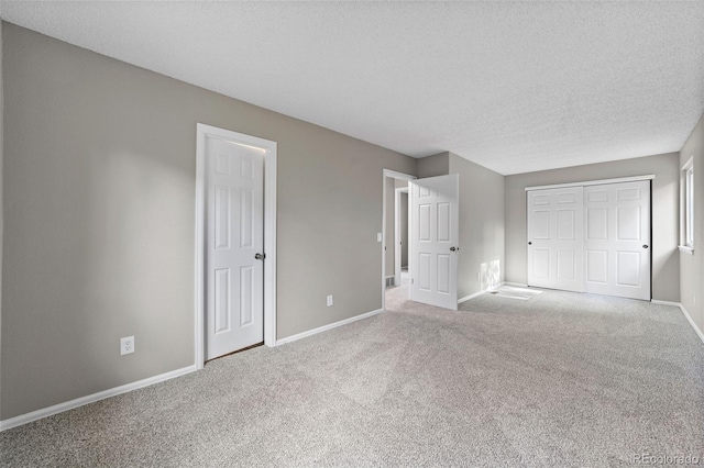 unfurnished bedroom featuring a closet, a textured ceiling, and light carpet