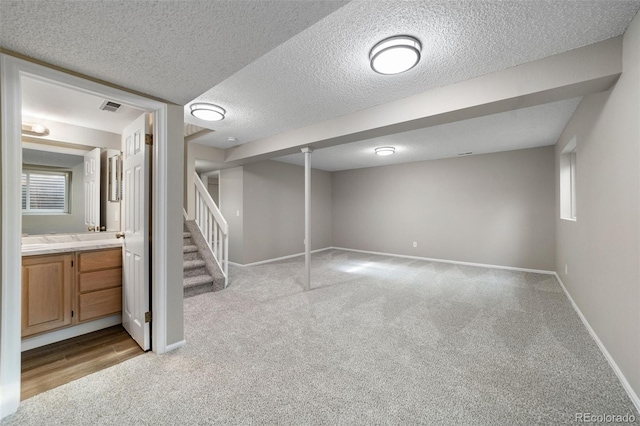 basement with light colored carpet, a textured ceiling, and plenty of natural light