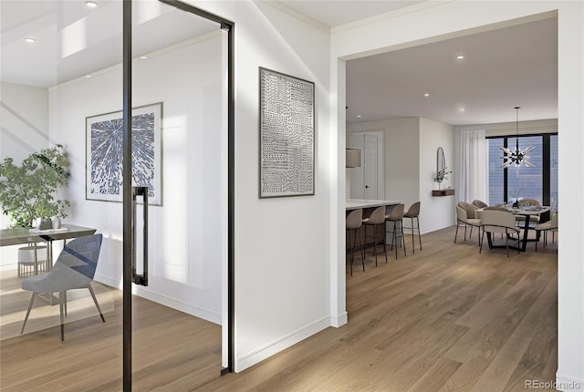 hallway featuring light wood finished floors, recessed lighting, baseboards, a chandelier, and crown molding