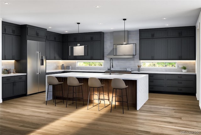kitchen with built in fridge, a sink, light countertops, light wood-type flooring, and recessed lighting