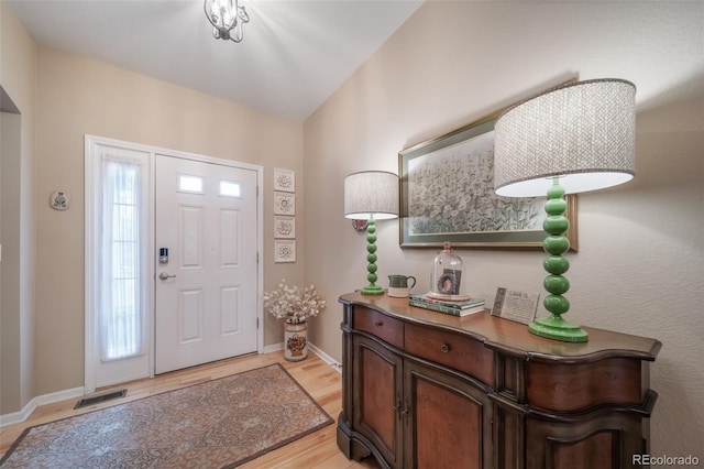 foyer entrance with baseboards, light wood-style flooring, and visible vents