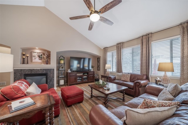 living area featuring ceiling fan, visible vents, wood finished floors, high vaulted ceiling, and a glass covered fireplace