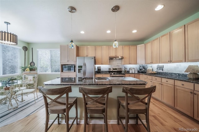 kitchen featuring appliances with stainless steel finishes, a sink, light brown cabinets, light wood-type flooring, and under cabinet range hood
